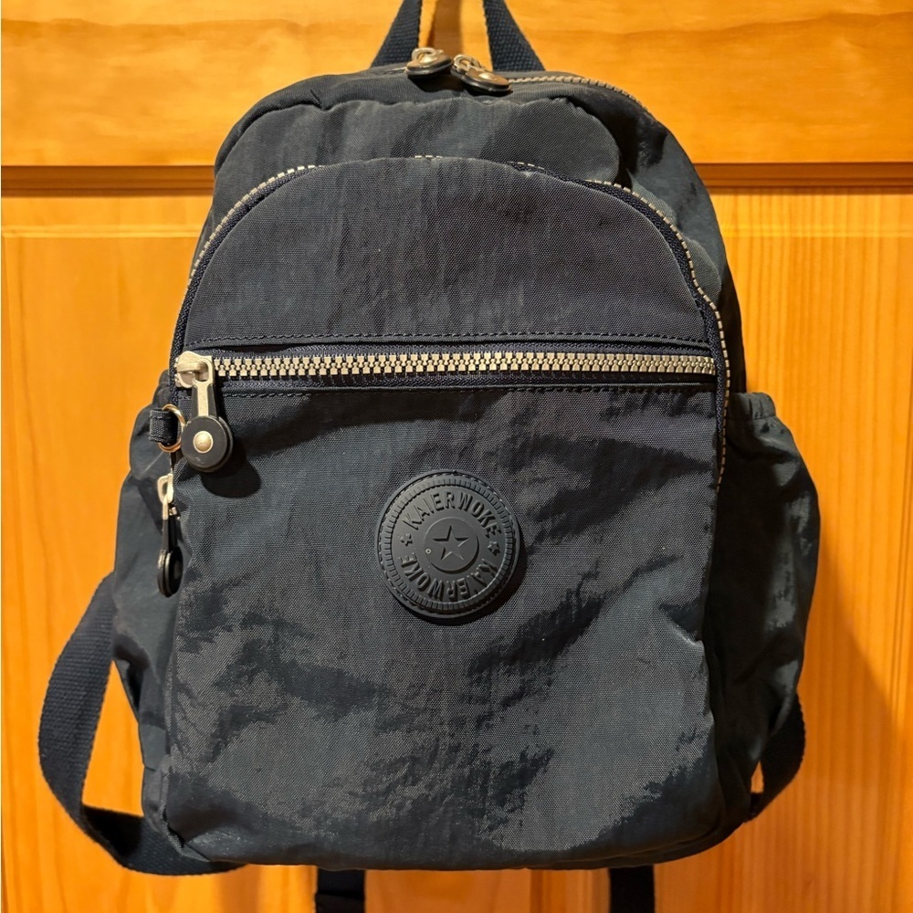 "Kaierwoke" backpack with silver zippers and a circular logo on the front